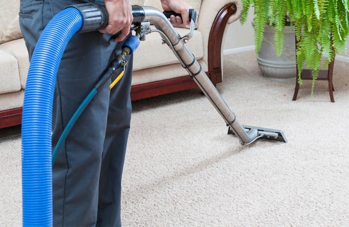 Worker cleaning carpet with vaccum cleaner.
