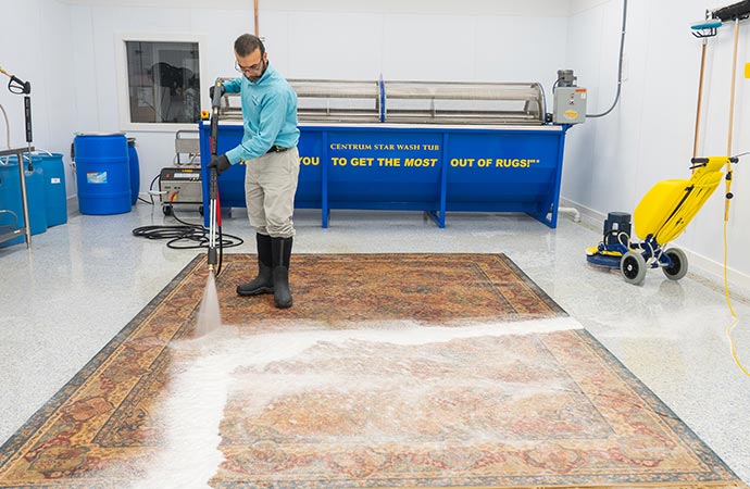 Blue dressed professional worker cleaing rug with his equipment